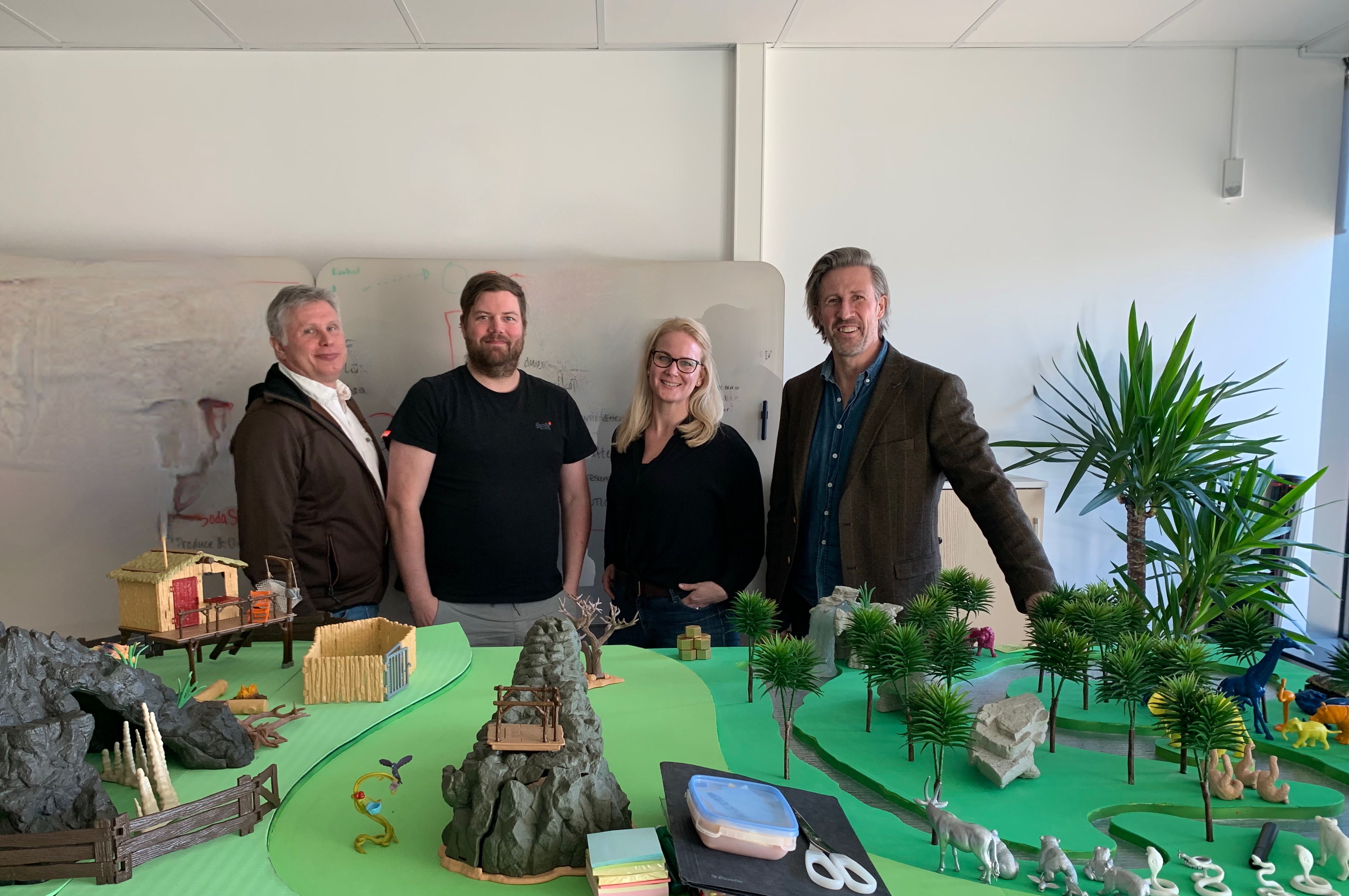 Team members discussing strategy around a detailed miniature landscape model